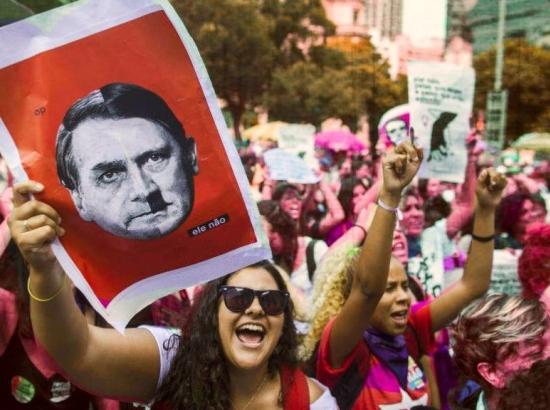 Brazilian protestor holds a placard depicting the face of President Jair Bolsonaro superimposed on the face of Adolph Hitler