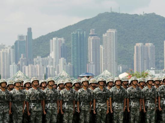 Hong Kong skyline behind People’s Liberation Army soldiers at Stonecutters Island naval base in Hong Kong, June 2019