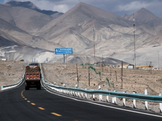 a cargo truck drives along a new highway in mountainous Central Asia
