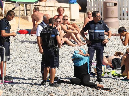 burkini-clad woman surrounded by police on beach in France in 2016