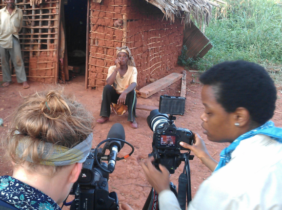 fixer helps a Western photojournalist set up a shot in a village in Africa