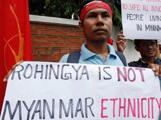 Burmese nationalist protester holding banner denying Rohingya ethnicity