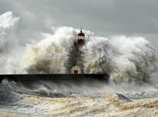 photo of a lighthouse overwhelmed by huge storm surge wave