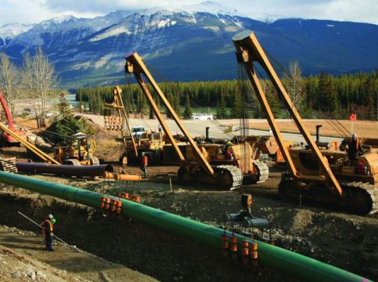 workers and machinery lay oil pipeline in Canadian Rocky Mountains