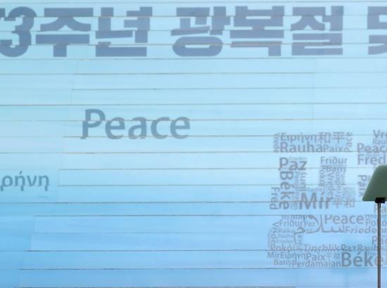 South Korean minister at conference podium with backdrop showing word Peace in numerous languages
