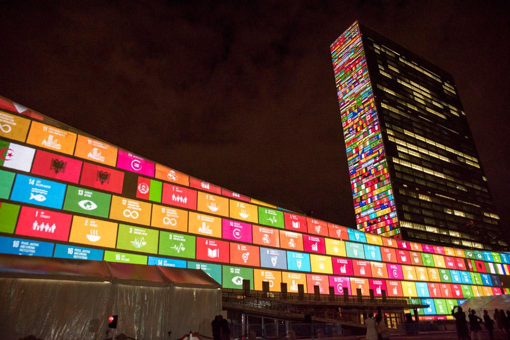 walls of the UN building in New York lit up with color-coded SDG logos