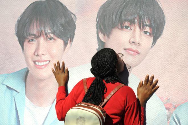 fan kissing the poster-enlarged face of a BTS member