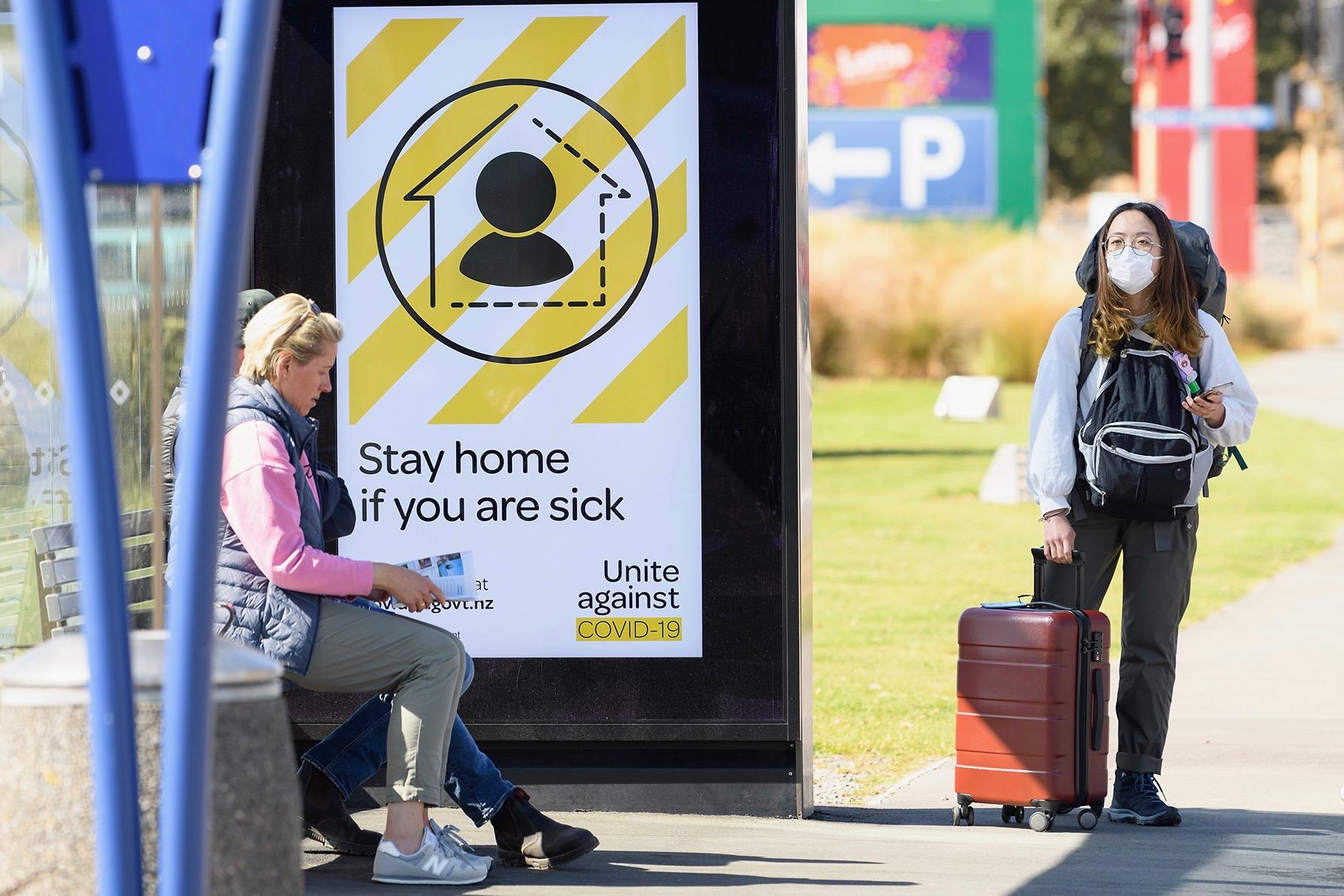 Asian traveler wearing a face mask at a bus stop near Christchurch