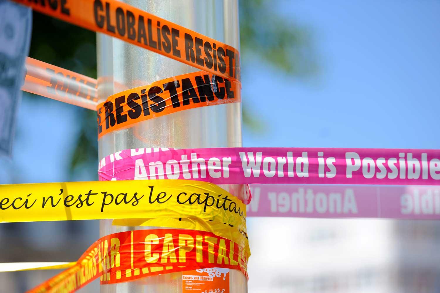 tape with words related to neoliberalism attached to a pole