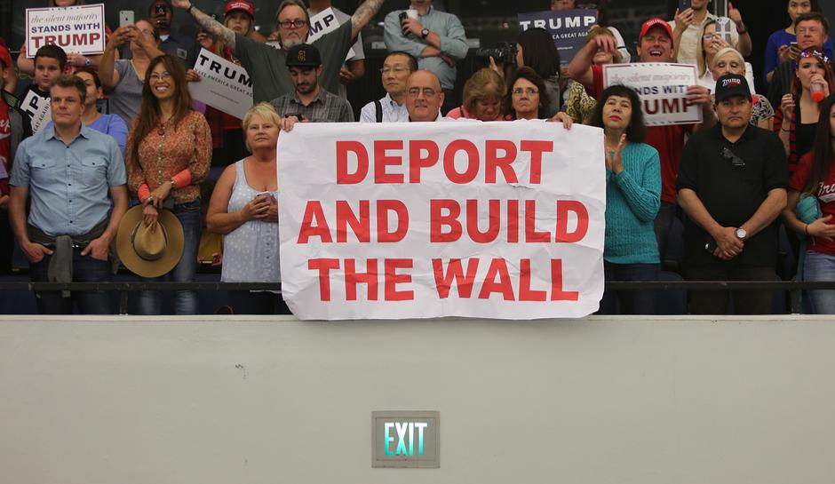Trump supporters at rally hold up sign reading 'Deport and Build the Wall'