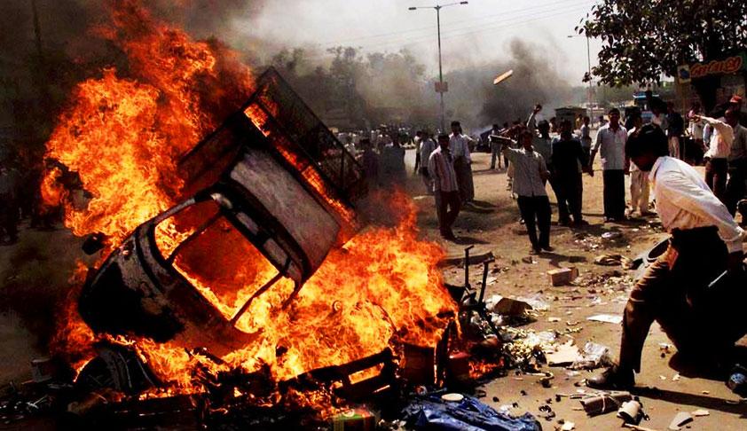 rioters surround a flaming vehicle in Ahmedabad, India in February 2002 during the violence and massacres in Gujarat state