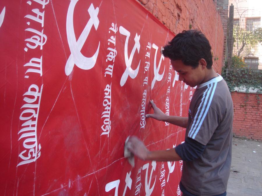 man puts up posters for Nepal Workers Peasants Party in Thamel, Nepal, 2008