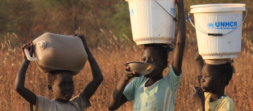 African children carry on their heads jugs and containers of water and food