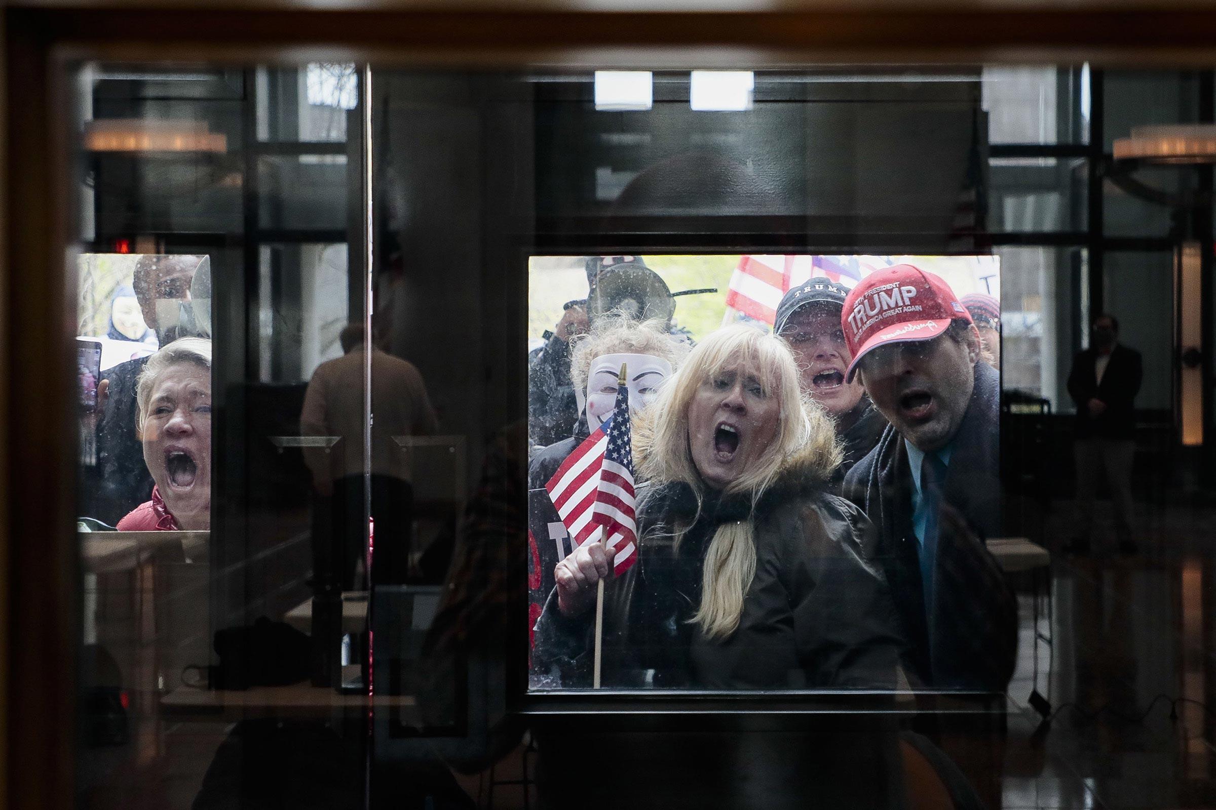 maskless protestors wearing Trump hats press against the windows of the statehouse in Columbus, Ohio in April 2020 to protest COVID-19 measures