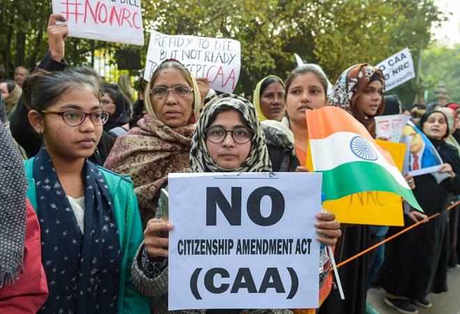 Indian women gathered in protest hold up an anti-CAA banner