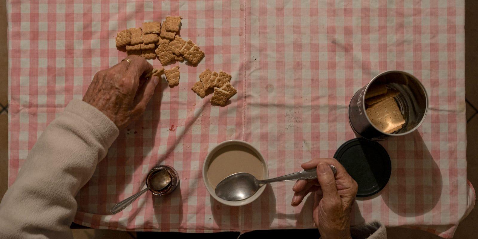 an elderly man eats alone at table in San Fiorano, Italy