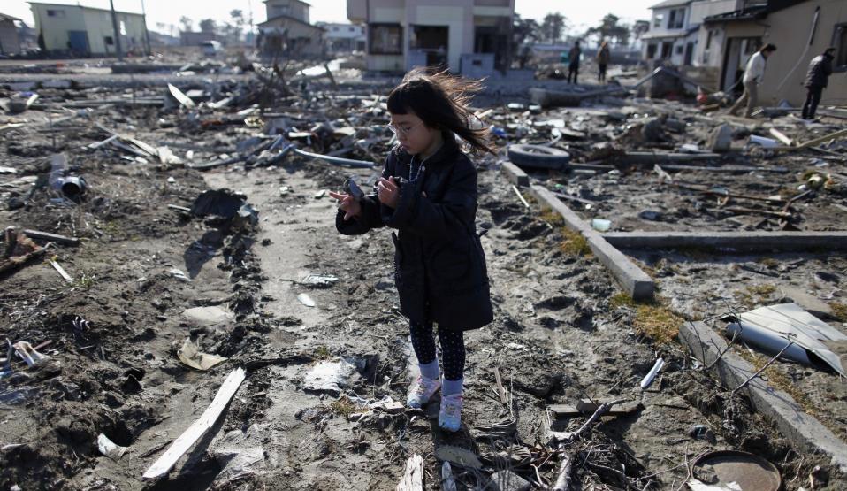 girl at the site of her family’s destroyed home in Miyagi Prefecture, one year after its destruction in the March 2011 earthquake/tsunami disaster