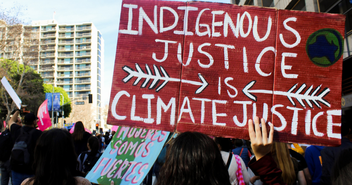 demonstrator holding placard reading Indigenous Justice Is Climate Justice