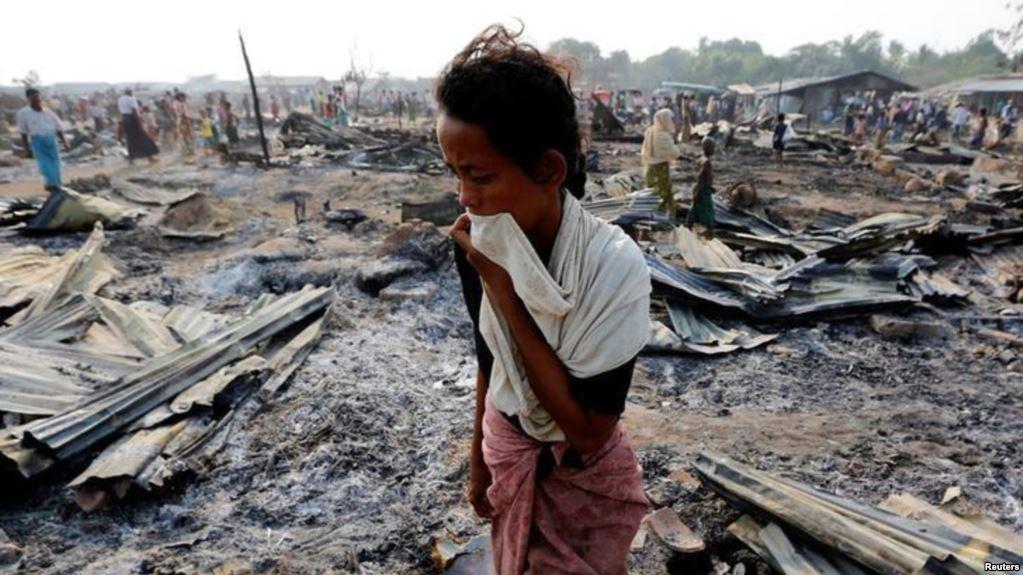 woman walks among burned ruins camp for internally displaced Rohingya Muslims near Sittwe