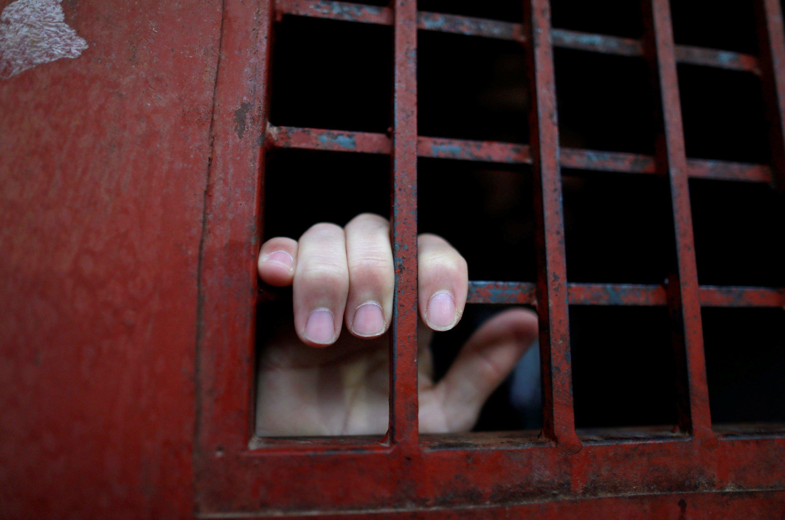 ISIS prisoner hand on jail cell bars