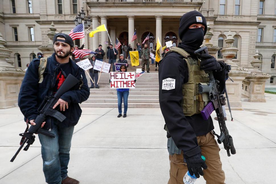 Protesters carry rifles at the steps of the State Capitol building in Lansing, Michigan