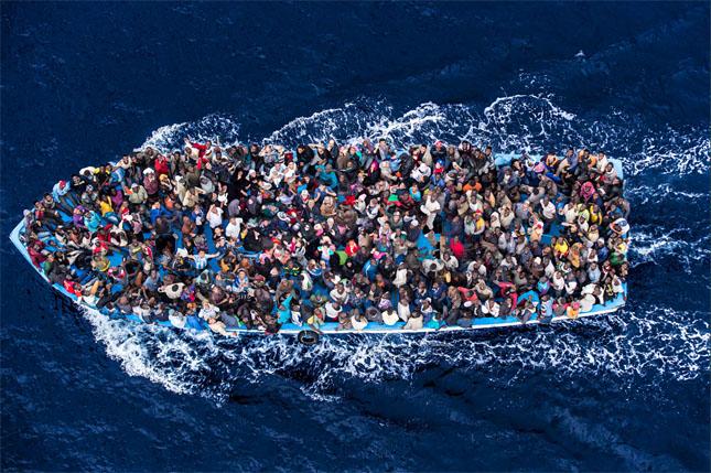 aerial overhead photo of fishing boat dangerously overcroweded with fleeding refugees