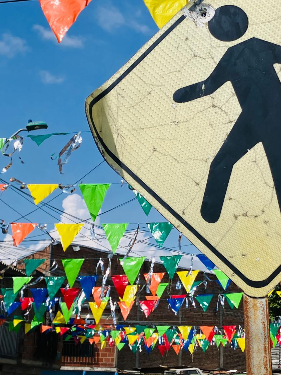 Banners flutter in the wind in anticipation of the end-of-year festivities in a marginal neighborhood of Cali. In the foreground, a “yielding” traffic sign with a bullet hole. Will life triumph? | Photo by Jaime Alves 