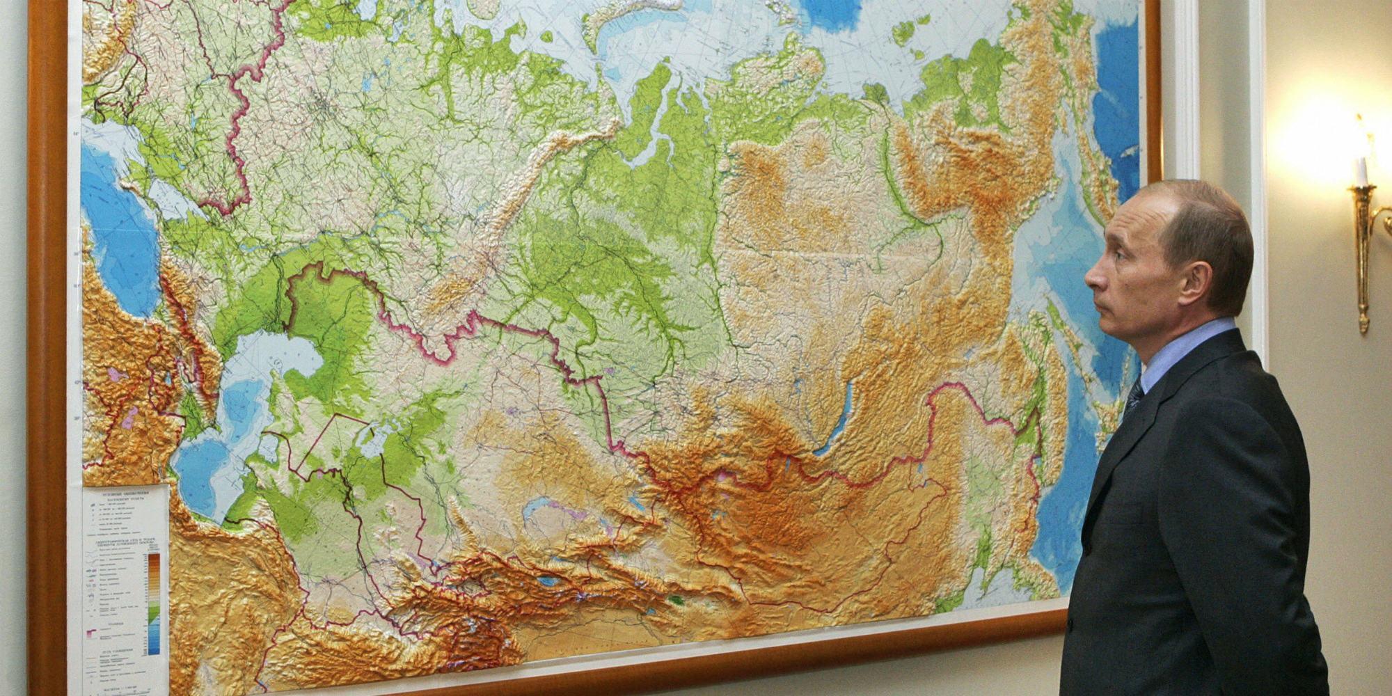 Vladimir Putin stands before large map of Eurasia
