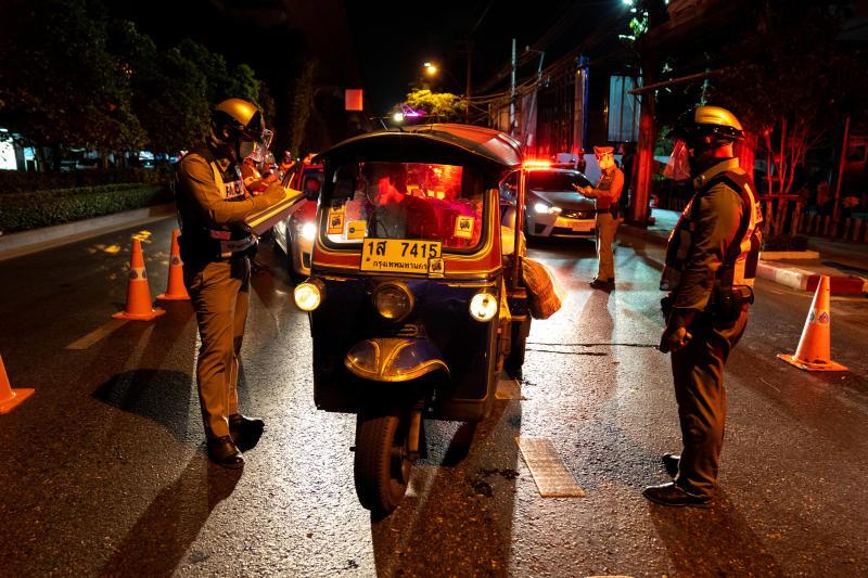 Police question people at a checkpoint in Bangkok in early April, 2020