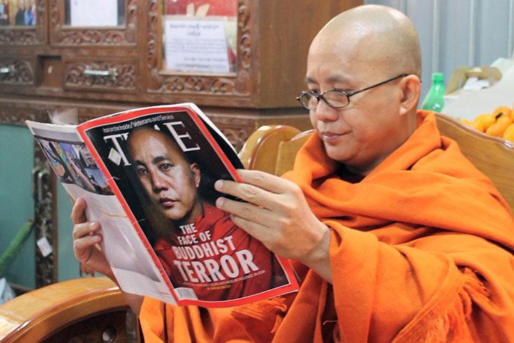 Burmese Buddhist monk Ashin Wirathu reads issue of TIME Magazine with his face on cover as 'The Face of Buddhist Tereror'