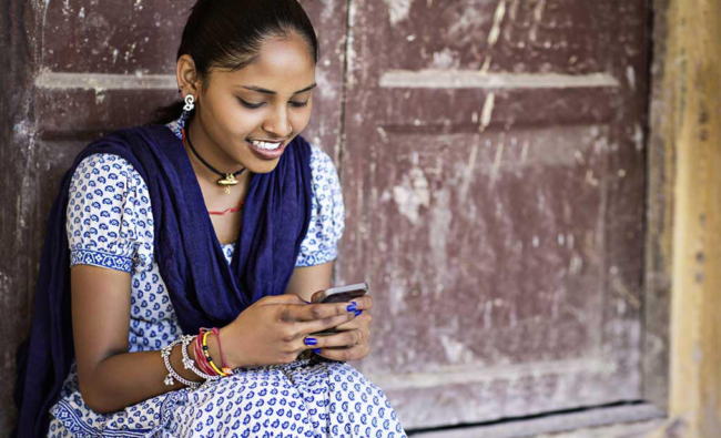 smiling Indian woman attends to something on her cellphone screen
