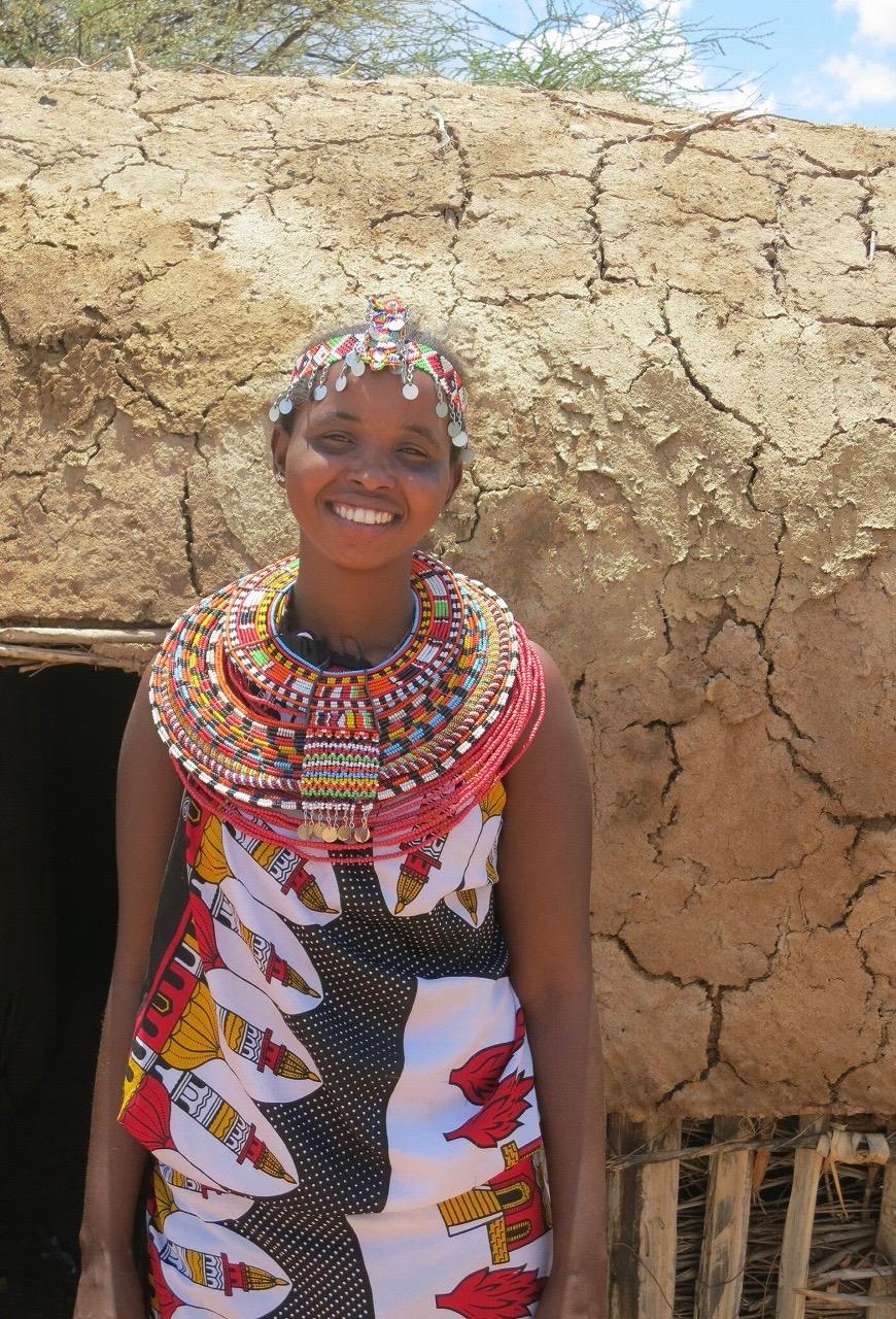 indigenous woman in front of traditional hut in Kenya