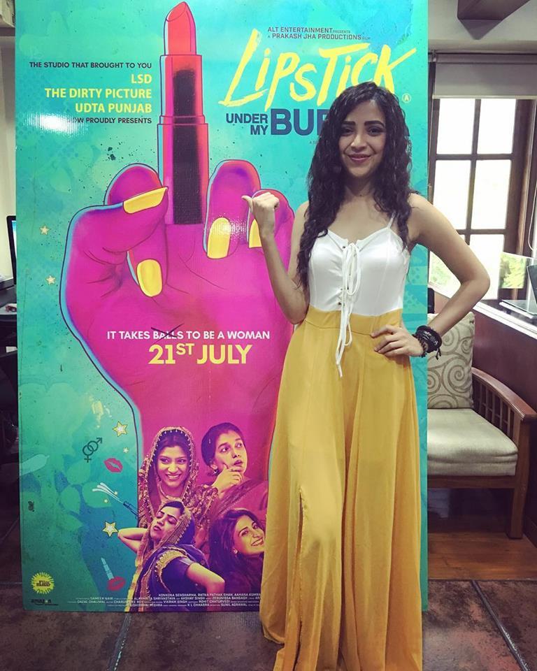 woman stands next to large marketing poster for the film 'Lipstick Under My Burkha'