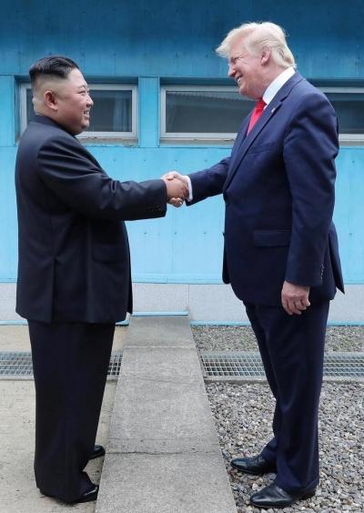 Donald Trump shakes hands with Kim Jong-un