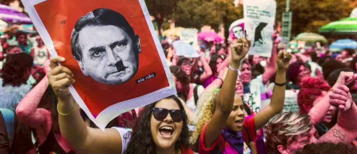 Brazilian protestor holds a placard depicting the face of President Jair Bolsonaro superimposed on the face of Adolph Hitler