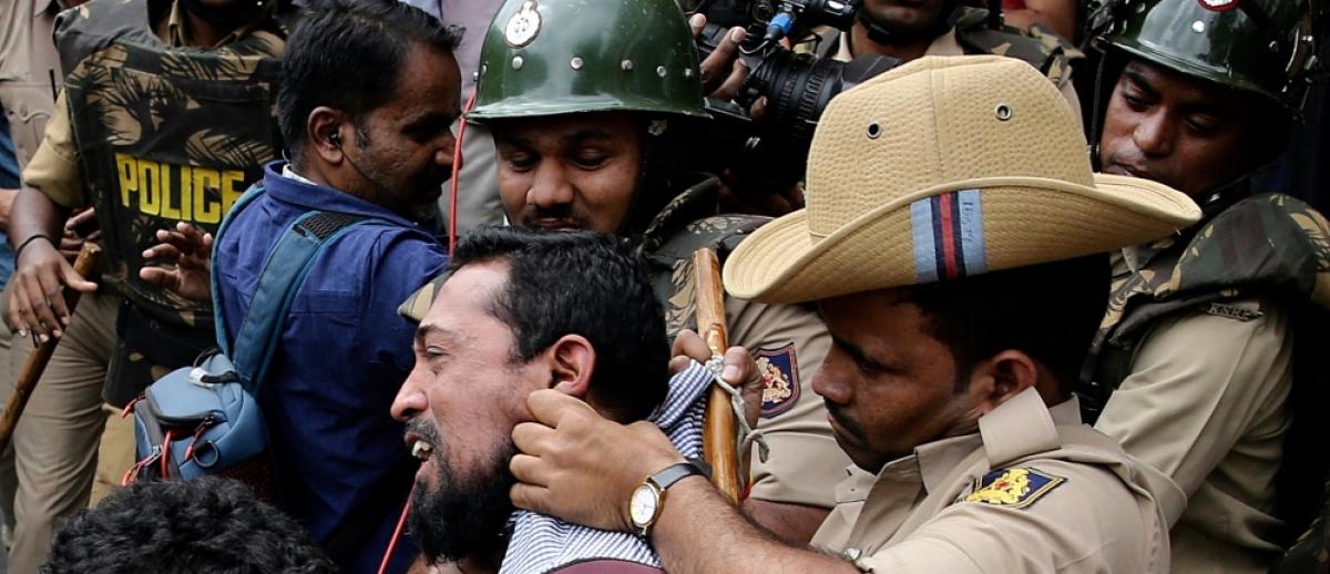 Indian policemen detain people during a protest against the citizenship law in Bangalore