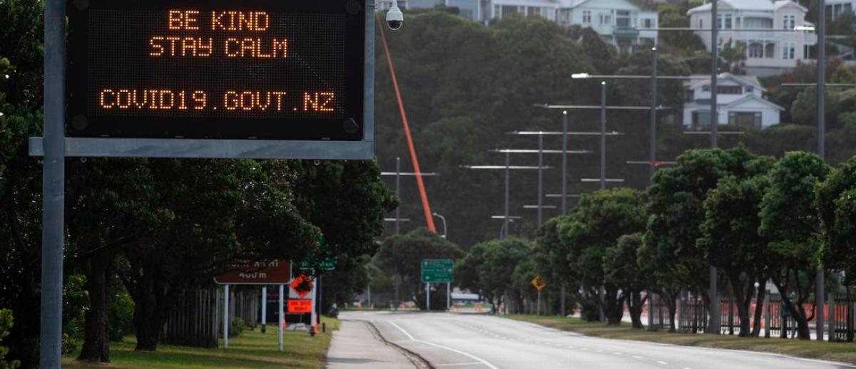 an empty thoroughfare with a road sign message from the New Zealand government  reading Be Kind - Stay Calm