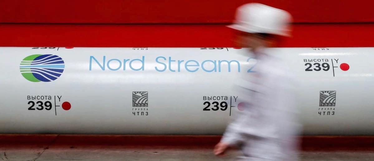 worker passes by a section of pipeline labeled Nord Stream 2