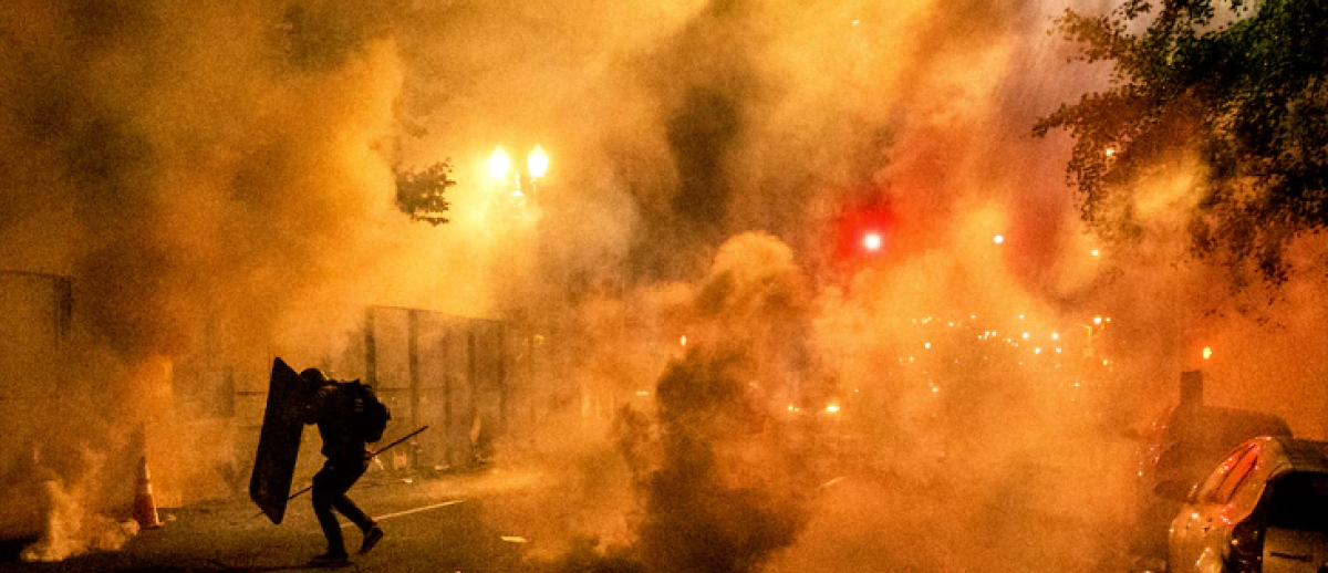 2020 Black Lives Matter protester silhouetted by smoke and tear gas in Portland, Oregon