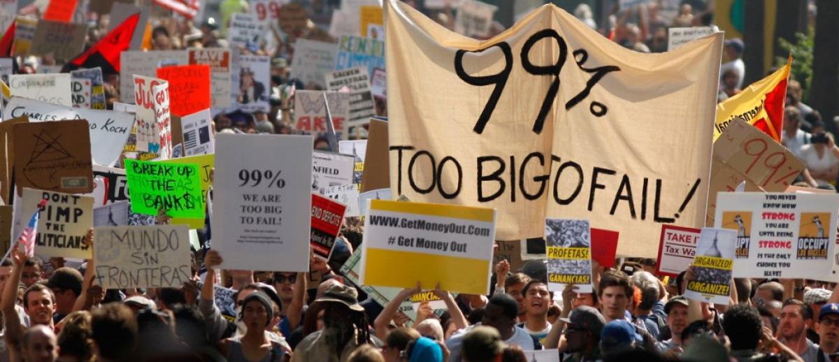 protest banner reads '99% Too Big To Fail'