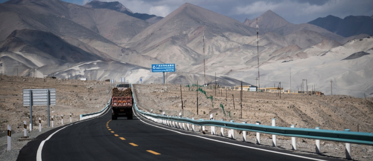 a cargo truck drives along a new highway in mountainous Central Asia