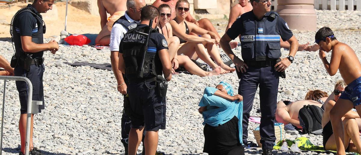 burkini-clad woman surrounded by police on beach in France in 2016