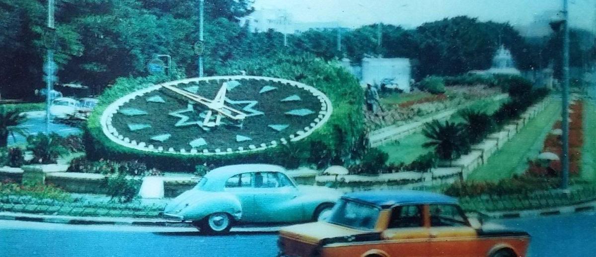 vintage photo of cars driving around flower clock at Sa'at Al Zouhour Square Alexandria, Egypt