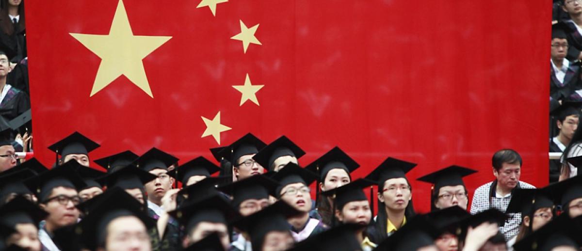 Chinese students attend graduation ceremonies with Chinese flag in background