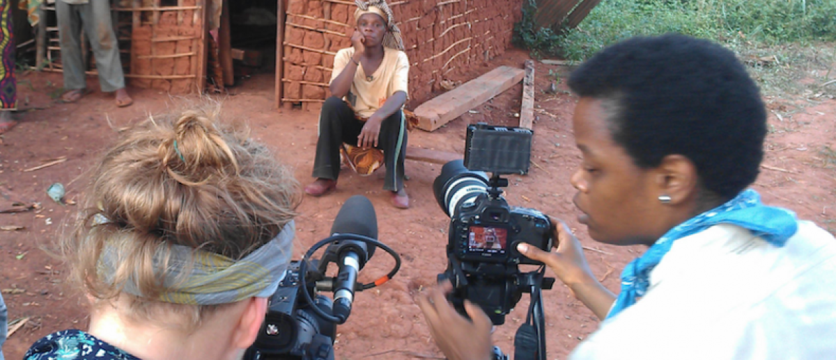 fixer helps a Western photojournalist set up a shot in an African village