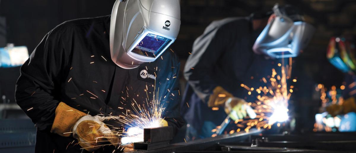 a line of masked welders at work