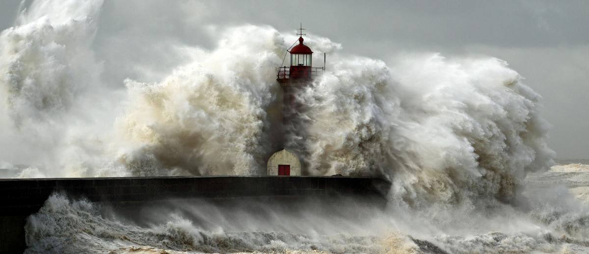 photo of a lighthouse overwhelmed by huge storm surge wave