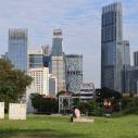 A migrant worker rests in a barren field against the backdrop of Singapore’s financial district.