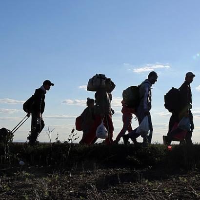 Migrants carrying luggage and walking in single file line