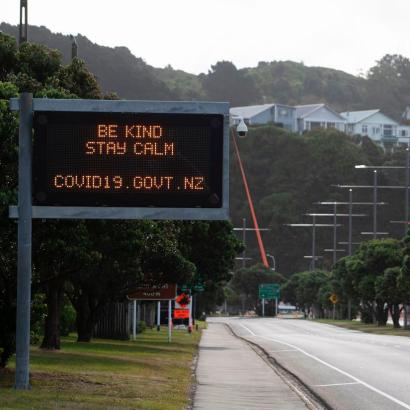 an empty thoroughfare with a road sign message from the New Zealand government  reading Be Kind - Stay Calm